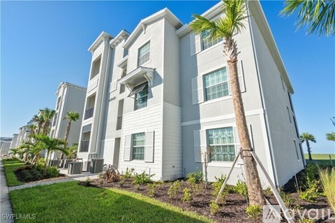 A white apartment building with a palm tree in front.