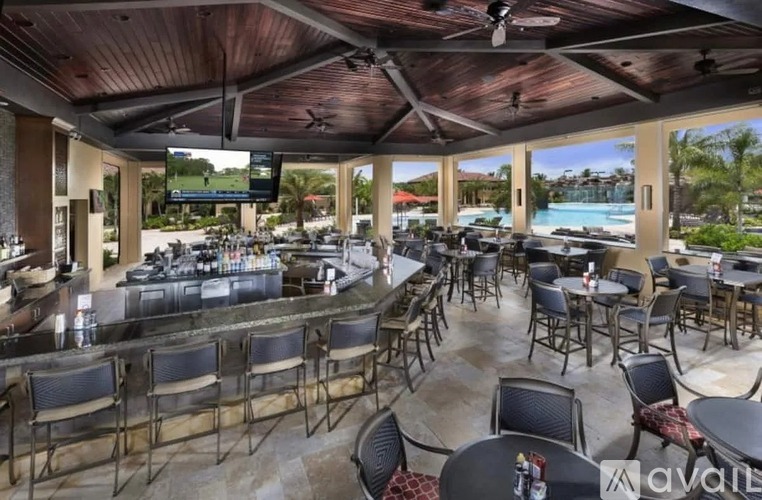 A restaurant with a wooden ceiling and tables and chairs overlooking a pool.