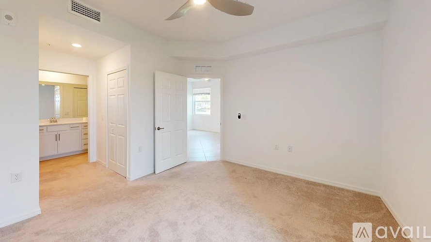 A spacious room with a ceiling fan and a door leading to another room.