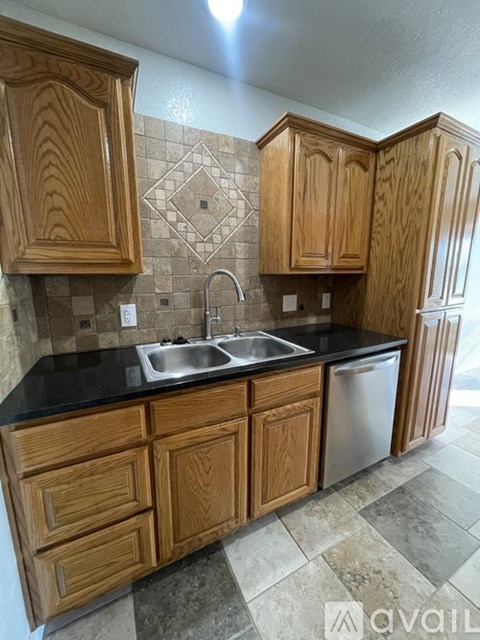 A kitchen with wooden cabinets and a black countertop.
