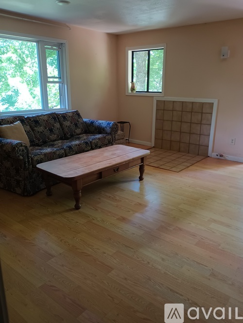 A living room with a couch, coffee table, and a window.