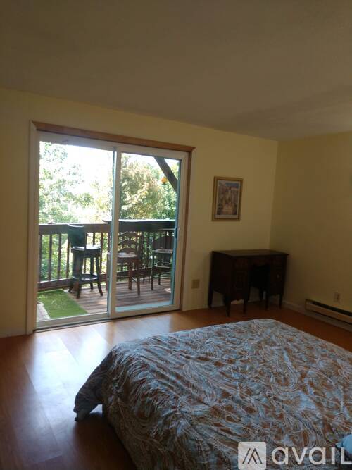 A bedroom with a bed, a piano, and a sliding glass door leading to a patio.