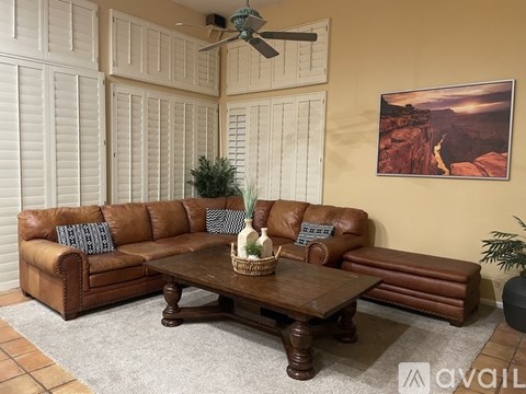 A living room with a brown leather couch and a wooden coffee table.