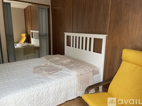 A bedroom with a white bed and a yellow chair.