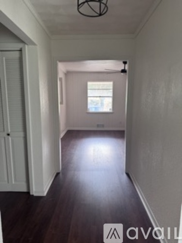 A hallway with a wooden floor and white walls.