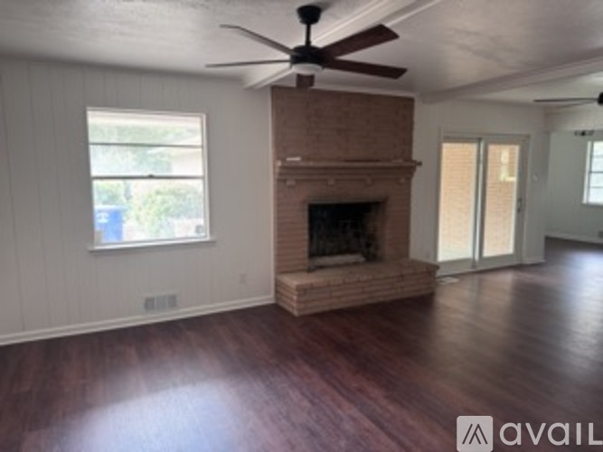 A living room with a fireplace and a ceiling fan.