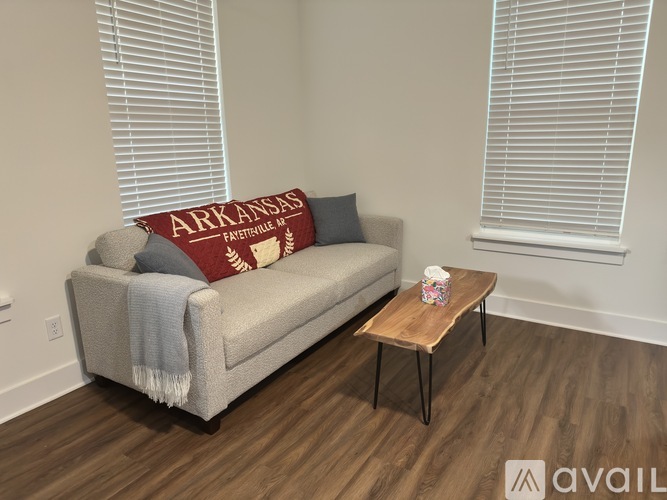 A living room with a couch, a pillow, a blanket, a coffee table, and a window with blinds.