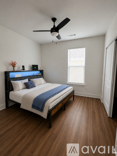 A bedroom with a bed, a ceiling fan, and a window.
