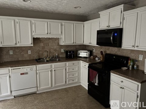 A kitchen with white cabinets and black appliances.