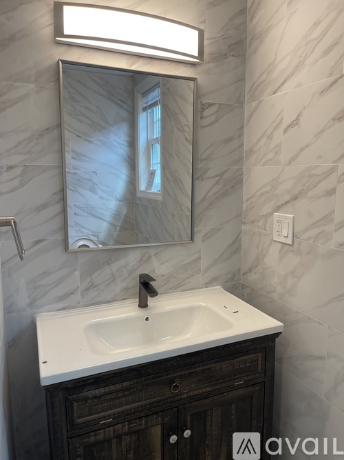 A bathroom with a marble wall and a white sink.