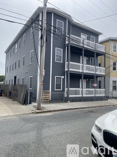 A grey building with a white car parked in front.