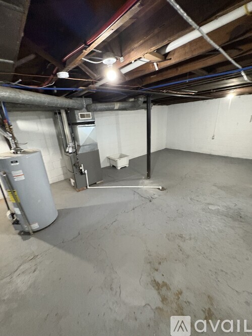 A spacious, unfinished basement with a concrete floor and exposed pipes and ducts.