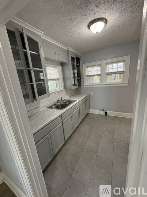 A kitchen with grey cabinets and a white sink.