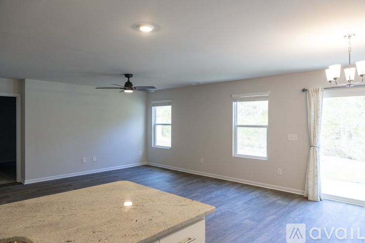 A spacious room with a ceiling fan and two windows.