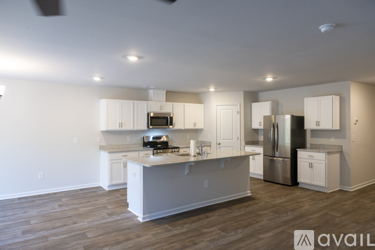 A kitchen with white cabinets and a wooden floor.