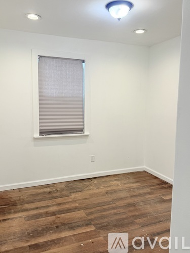A room with wooden flooring and a window with blinds.