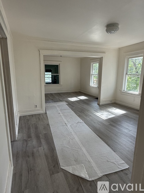 A room with wooden flooring and white walls is available for rent.