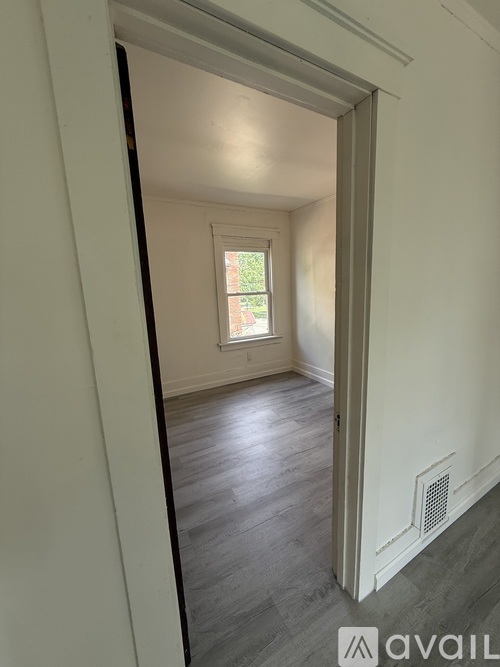 A room with a window and a wooden floor.