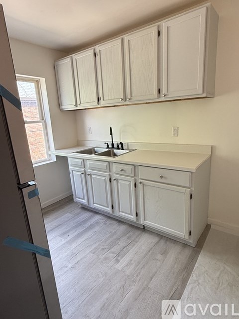 A kitchen with white cabinets and a wooden floor.