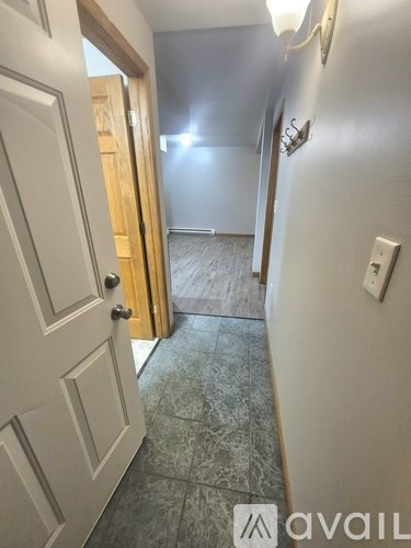 A hallway with a door on the left and a light switch on the wall.