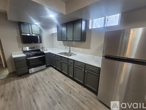 A modern kitchen with a stainless steel refrigerator and wooden flooring.