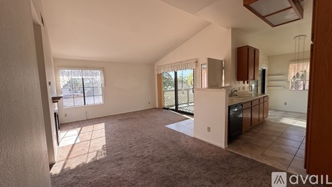 A spacious living room with a kitchen area in the background.