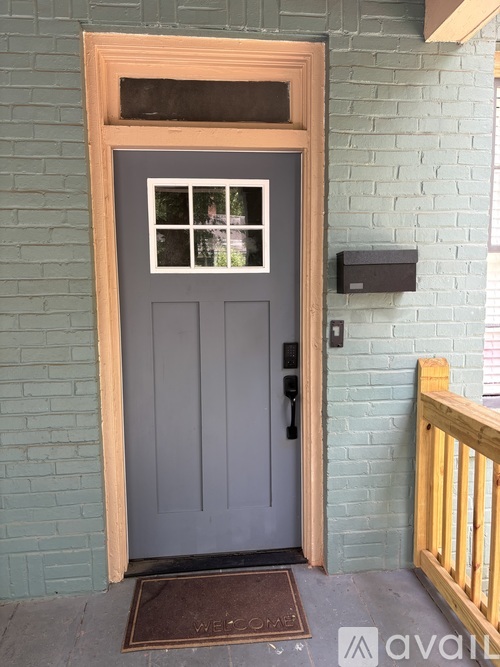 A grey door with a window in the middle and a wooden frame.