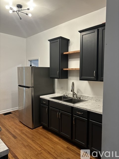 A kitchen with black cabinets and a stainless steel refrigerator.
