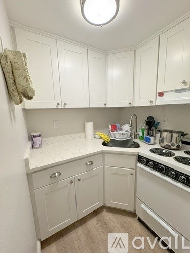 A kitchen with white cabinets and a white stove top oven.