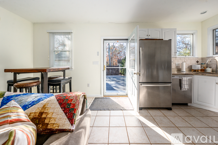 A kitchen with a refrigerator, sink, and a dining table with chairs.