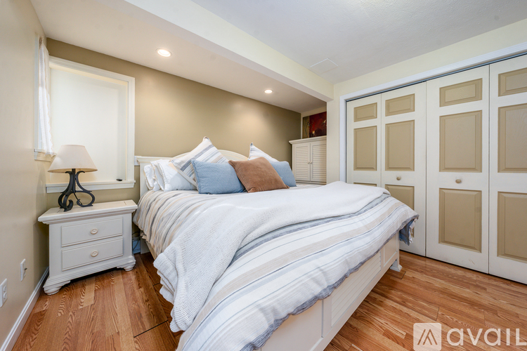 A bedroom with a large bed and a nightstand with a lamp.