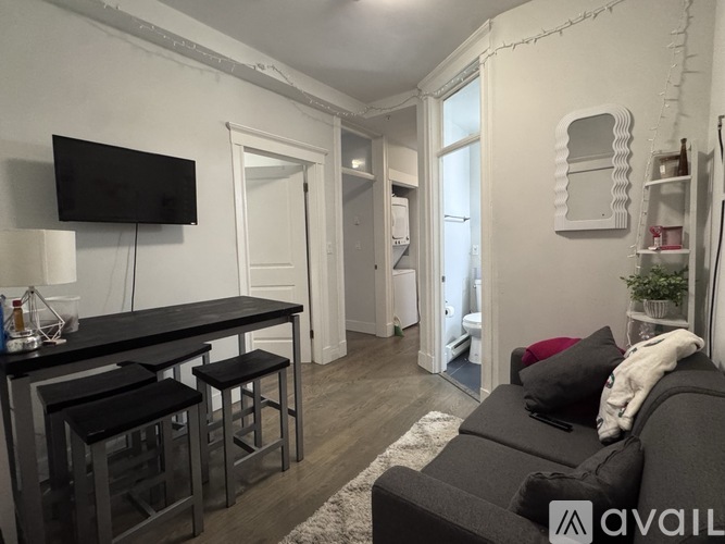 A living room with a black couch and a television on the wall.