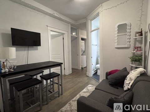 A living room with a black couch and a television on the wall.