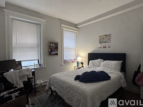 A bedroom with a bed, a chair, and a window with blinds.
