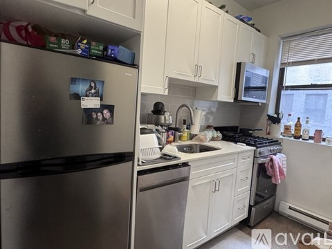 A kitchen with white cabinets and a stainless steel refrigerator.