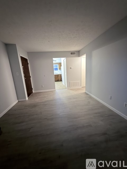A spacious room with wooden flooring and white walls.