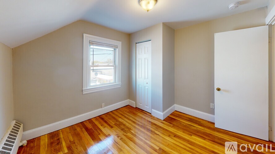 A room with wooden floors and a window is available for rent.