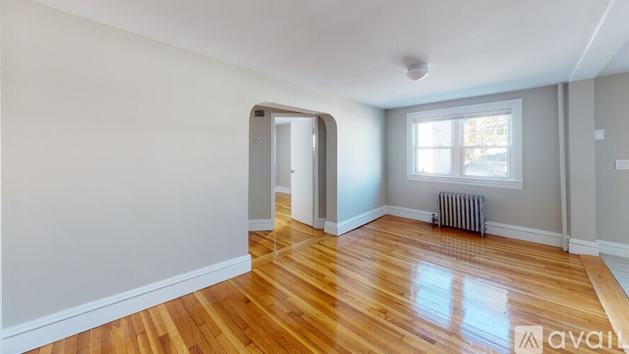 A room with wooden floors and a window with a radiator beneath it.