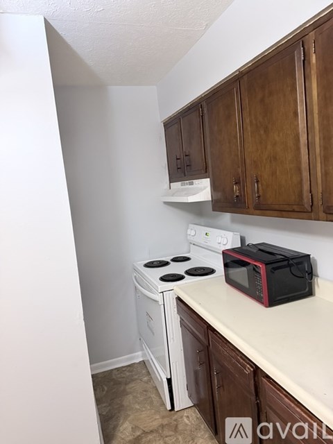 A kitchen with a white stove and wooden cabinets.