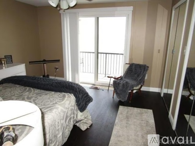 A bedroom with a bed, chair, and sliding glass door.