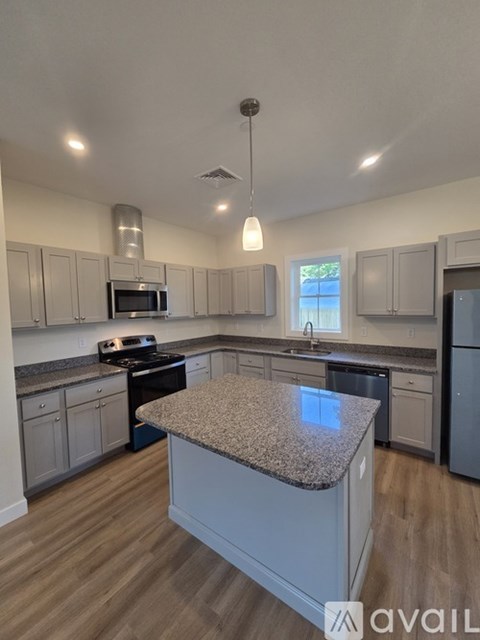 A kitchen with a granite countertop and wooden flooring.