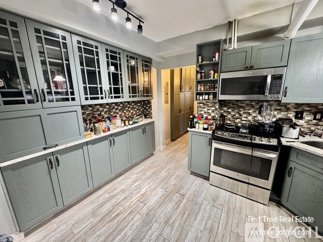 A kitchen with grey cabinets and a tile backsplash.