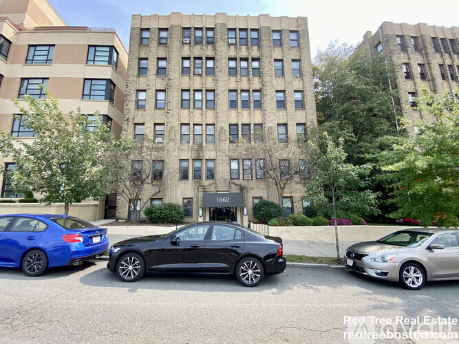 Three cars parked in front of a building with the number 1662 on it.