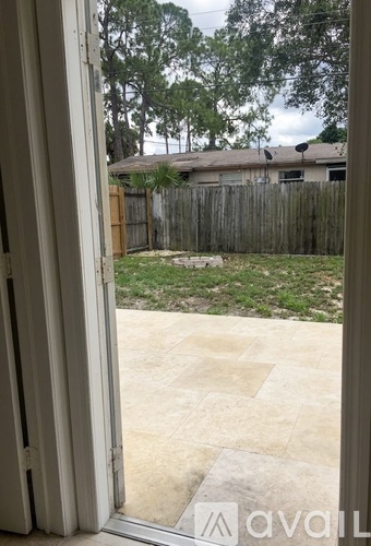 A view from inside a room looking out to a backyard with a fence and trees.