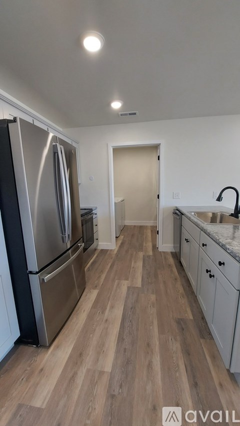 A kitchen with a refrigerator, sink, and cabinets.