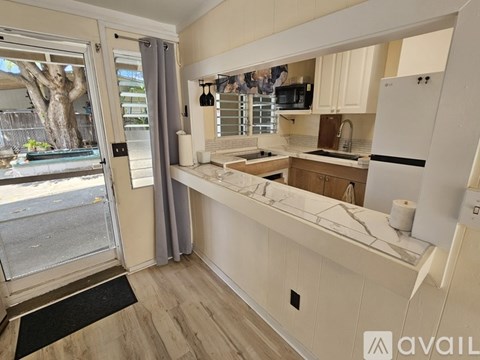 A modern kitchen with a white countertop and wooden cabinets.