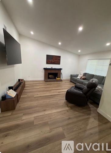 A living room with a fireplace and a flat screen TV mounted on the wall.