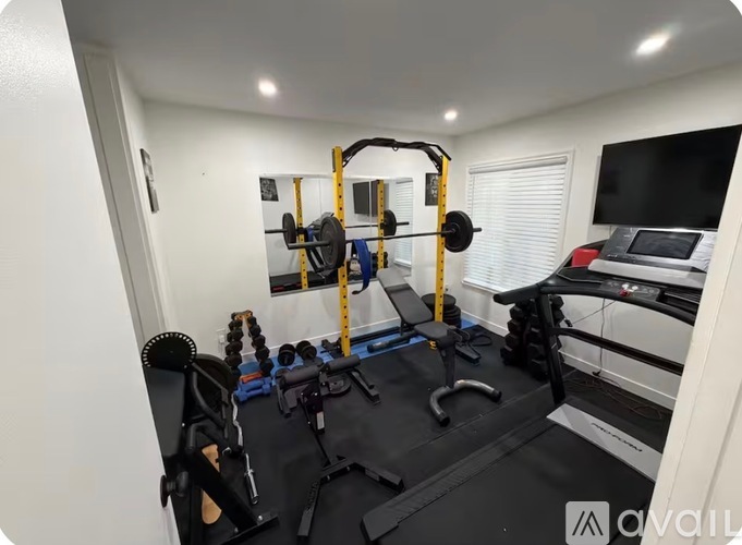 A home gym with a variety of equipment including a squat rack, bench, and weights.
