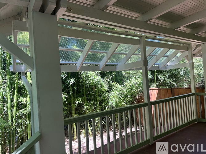 A balcony with a green railing and a roof with skylights overlooking a garden.