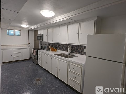 A kitchen with white cabinets and a grey floor.
